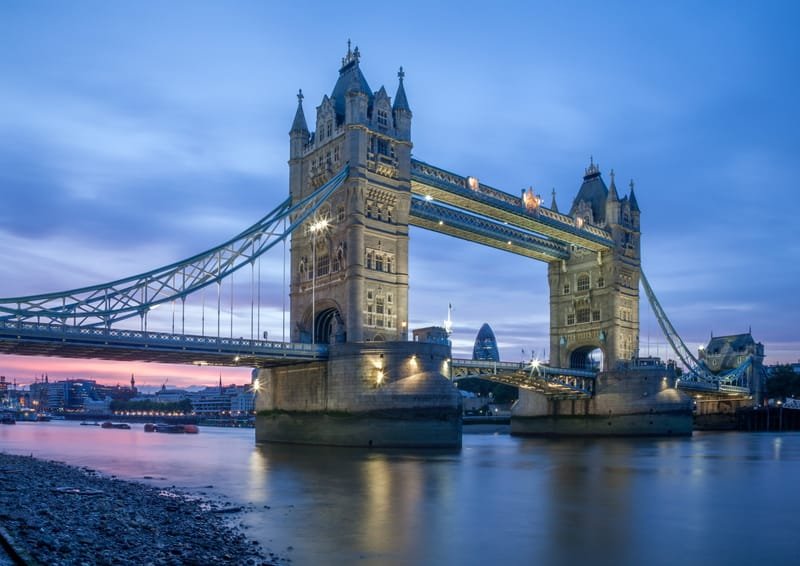 Tower Bridge lit at dusk from the pebble foreshore, pink and blue sky