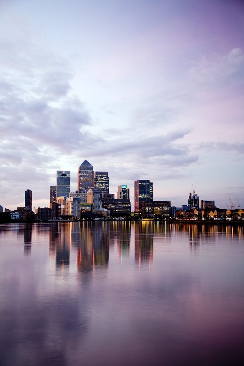 Canary Wharf skyline reflected in the river under a pink dawn sky