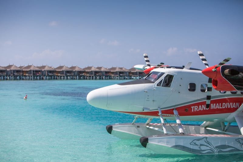 Trans Maldivian seaplane moored beside overwater villas on a turquoise lagoon, Maldives