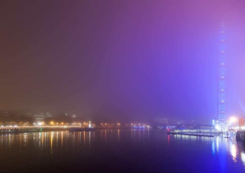 Fog glowing violet over the Thames at night, riverside lights fading into the haze