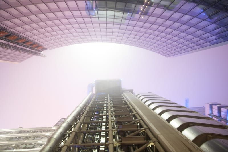 Looking up between the Lloyd's building's steel gantries into white fog