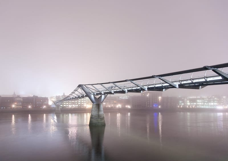 The Millennium Bridge disappearing into fog above a glassy Thames