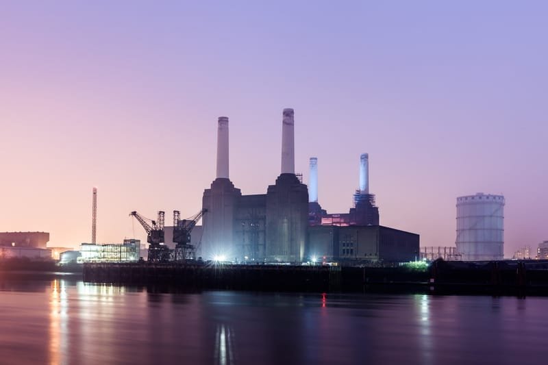 Battersea Power Station's four chimneys lit at dusk across the Thames